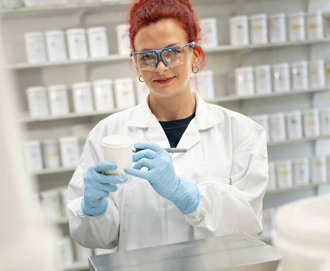 Woman with blue rubber gloves marking a label in a pharmaceutical environment